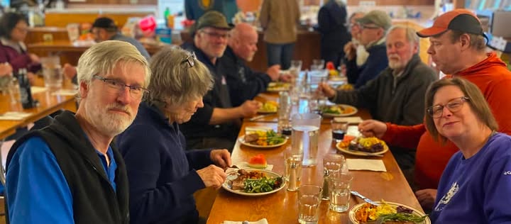 Club members sharing a potluck meal at a long table in the lodge